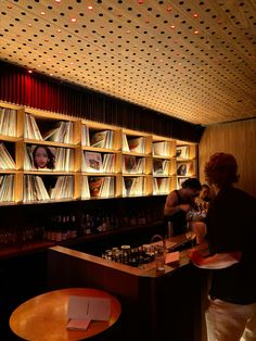 people are standing at the bar with records on the wall