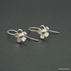 Hand made sterling silver flower earrings. The silver flowers measure 10mm. in diameter and have been hand  saw pierced from sturdy silver sheet To the centre of each flower there is a small silver bead. The earrings are secured with fixed silver hook fittings. All my jewellery comes in a presentation gift box.  All my designs are hand made and no two are exactly the same. Thank you for visiting. Please note that international shipping fees do not include possible custom charges for your country and you will be solely responsible for payment of these charges.  We are required by law to fully disclose the contents and value of the items in your package for Customs purposes.  Your local customs office will be able to provide you with further information on possible import duties and other ch Sterling Silver Jewelry With 3d Flowers In Silver, Delicate Silver Flower Earrings Nickel-free, Delicate Silver Flower Earrings Nickel Free, Delicate Silver Earrings With Flower Charm, Delicate Silver Nickel-free Flower Earrings, Silver Delicate Nickel-free Flower Earrings, Sterling Silver Jewelry With 3d Flower Design, Sterling Silver Flower Charm Earrings, Delicate Silver Flower Earrings For Anniversary