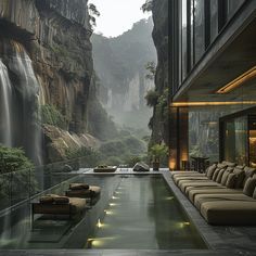 an indoor swimming pool with lounge chairs and waterfall in the background, surrounded by greenery