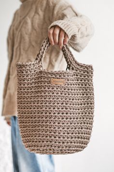 a woman holding a crocheted bag in her hands