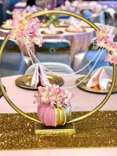 a pink and gold centerpiece with flowers on it