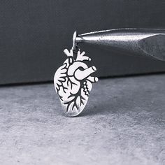 This Sterling Silver Anatomical Heart Flat Charm comes with a 5mm jump ring. You can also avail it with a Sterling Silver Chain (optional). DETAILs * Sterling Silver Anatomical Heart Pendant (22 x 12 x 1 including ring), marked 925 * Sterling Silver Rolo Chain 1.5mm marked 925 Italy (optional) NEED some CHAIN?  ► https://www.etsy.com/shop/femmeskicharms?section_id=51104264 Back to SHOP  ► http://www.etsy.com/shop/femmeskicharms PLEASE NOTE ►FREE Shipping for all domestic purchases above $35 through USPS ground advantage. ►All photos have been enlarged to show detail, please refer to item dimension Follow ►me on SOCIAL MEDIA: * Pinterest: https://www.pinterest.com/femmeskietsy * Facebook: https://www.facebook.com/Femmeski Thank you and come back again soon. ♥FemmeskiCharms♥ Anatomical Heart Pendant, Anatomy Heart, Cardiologist Gift, Heart Doctor, Doctor Gift, Heart Surgery, Pendant Heart, Anatomical Heart, Human Heart