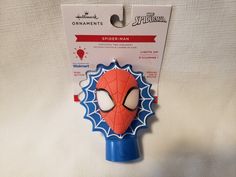 a spider man shaped object is in the package for sale on a white tablecloth