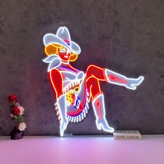 a neon sign with a man in a mexican outfit on it next to a flower vase