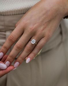 a close up of a person's hand with a diamond ring on their finger