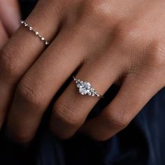 a woman's hand with a diamond ring on her left hand and two diamonds on the middle finger