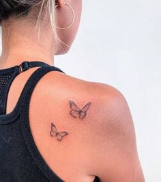 a woman with a butterfly tattoo on her upper arm and behind her back is a black tank top