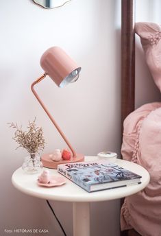 a white table with a pink lamp and books on it in front of a mirror