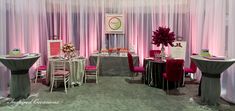 a room filled with tables and chairs covered in pink draping next to curtains