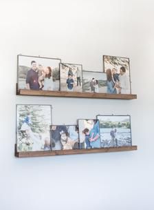 three wooden shelves with pictures hanging on the wall and one shelf holding two photos,