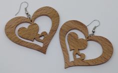 two wooden heart shaped earrings with hearts cut out of them on a white table top