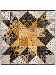 a quilt made with yellow, black and white fabrics on a tablecloth that has an image of a star in the center