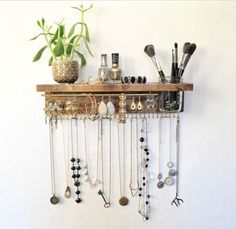 a wooden shelf with various jewelry hanging from it and a potted plant next to it