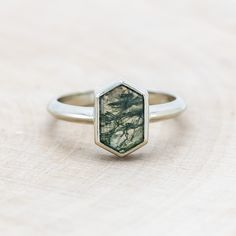 a close up of a ring on a wooden surface with a tree in the background