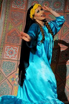 a woman in blue dress standing next to a wall