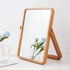 a mirror sitting on top of a table next to a vase with flowers