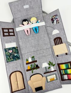 a doll house made out of felt with dolls on the top floor and furniture below