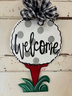 a welcome sign hanging from the side of a building with a bow on it's head