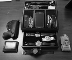 a black and white photo of an assortment of watches in a box with leather wallets