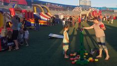 two people playing with cups in front of an inflatable bouncy castle