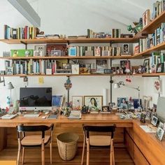 a home office with lots of books on the shelves and desks in front of it