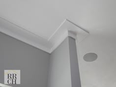 the corner of a room with a white ceiling and light fixture on it's side