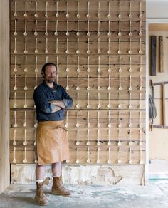 a man standing in front of a wooden wall with pegs attached to the wall