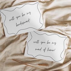 two paper signs with writing on them sitting on a bed sheet that says, will you be my bridesmaid? and will you be my maid of honor?