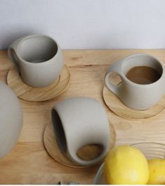 three cups and two lemons on a cutting board