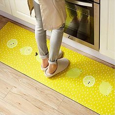 a person standing on a yellow mat in front of an oven with lemons and lime slices