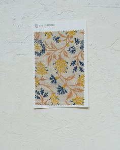 a piece of cloth hanging on the wall next to a paper with an orange and blue flower pattern