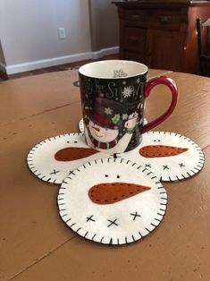 a coffee cup sitting on top of a wooden table next to a red mug holder