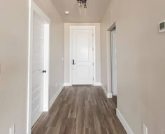 an empty hallway with white walls and wood floors is seen in this image from the front door