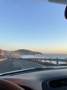 a car driving down the road next to the ocean