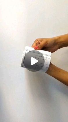 two hands holding up a piece of paper that has been taped to the wall with tape