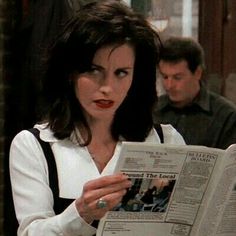 a woman reading a newspaper while sitting at a table