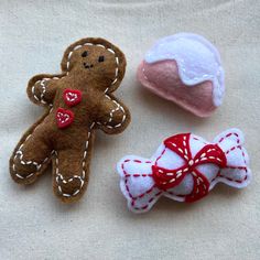 three different types of felt toys on a white cloth surface, one with a red bow and the other with a ginger