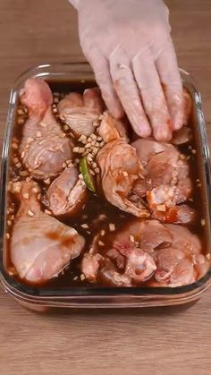 a person in white gloves is picking up some meat from a dish with sesame seeds