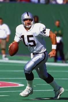 a football player running with the ball in his hand and people watching from the sidelines