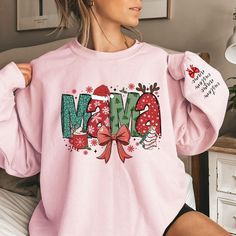 Make this holiday season extra special with our Custom Mama Claus Sweatshirt and Hoodie! This personalized Christmas sweatshirt allows you to add your children's names on the sleeves, making it a unique and thoughtful gift for moms, nana,gigi or grandmas. Whether you're getting cozy at home or heading out for festive gatherings, this custom sweatshirt adds a personal touch to the holiday spirit. It's the perfect Christmas gift for moms or grandmas who love to show off their family in style. Cele Mama Christmas Sweatshirt, Bow Christmas, Grandma Shirts, Mom Christmas, Xmas Shirts, Mama Sweatshirt, Coquette Bow, Custom Sweatshirts, Comfort Colors Tee