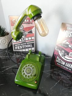 a green phone sitting on top of a table next to a book and planter