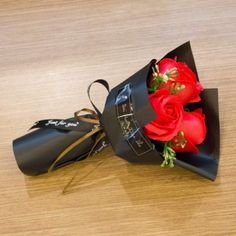 a bouquet of red roses sitting on top of a black paper bag