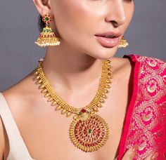 HAND CRAFTED JEWELLERY DESCRIPTION *Gold plated temple jewellery set *Gold plated necklace, has an embellished circular centrepiece, secured with drawstring fastening *A pair of embellished gold plated jhumka earrings, has a floral base, a dome-shaped dangler and pearl-like beaded drops *Secured with a post-and-back closure *Size:- Length of the necklace: 16 cm Length of the earrings: 5 cm *Material:- Material: Brass Plating: 24K gold-plated *Care:- Wipe with a clean cotton swab when needed NOTE All the raw material used in this product is of high quality and is handcrafted with love. Premium Quality and High craftsmanship 100% Satisfaction Guarantee: Long Lasting Plating, High-Quality Stones. Our jewellery is individually handcrafted by master artisans using meticulous crafting techniques Yellow Gold Round Kundan Necklace Temple Jewelry, Yellow Gold Round Kundan Necklace In Temple Style, Yellow Gold Round Kundan Temple Necklace, Temple Jewelry Sets With Latkans And Round Shape, Round Cutdana Jewelry For Puja, Yellow Gold Round Temple Necklace With Meenakari, Bollywood Style Round Jewelry For Puja, Kundan Temple Jewelry With Round Pendant, Temple Jewelry With Meenakari Round Pendant