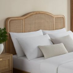 a bed with white sheets and pillows in a bedroom