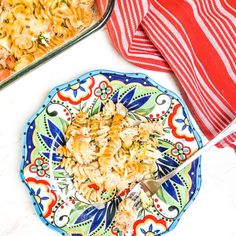 a plate with pasta and meat on it next to a casserole dish filled with chicken