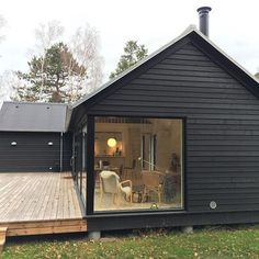 a black house with wooden decking and glass windows