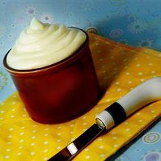 a red container with whipped cream sitting on top of a yellow napkin next to a spoon