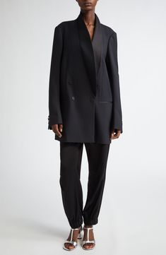 Van Noten's unique take on the tuxedo jacket means an oversized cut that draws attention to what makes it the pinnacle of formalwear, such as the balance struck between matte and sheen via satin covering the buttons, pocket openings and smoothly curved lapels. This style was represented in the Belgian designer's fall '24 runway show. 36" length (size Small) Double-breasted button closure Shawl collar Four-button cuffs Chest welt pocket; front welt pockets Lined 82% wool, 10% silk, 8% polyester D Tuxedo Blazer With Structured Boning, Modern Tailored Blazer Dress For Formal Occasions, Chic Semi-formal Tuxedo With Pressed Crease, Designer Evening Suit With Lapel Collar, Sleek Evening Blazer With Hidden Button Closure, Modern Notch Lapel Blazer Dress For Formal Occasions, Chic Formal Tuxedo For Fall, Modern Formal Blazer Dress With Notch Lapel, Chic Fall Tuxedo For Formal Occasions