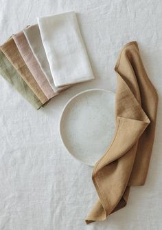 four folded napkins sitting on top of a white plate next to an empty bowl