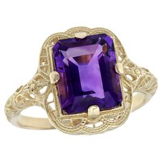 Crafted in stunning yellow gold, this vintage-inspired ring features a filigree band that gracefully tapers towards the front. Intricate scrollwork filigree adorns the shoulders of the band, adding exquisite detail. At the heart of the ring shines a magnificent 3.5 carat octagon purple amethyst, boasting a faceted emerald-cut and set securely within a prong setting. This ring is sure to turn heads and garner admiration wherever you go. CHARACTERISTICS Status: Made to order Origin: Thailand Metal Filigree Ring Gold, Gold For Sale, Amethyst Color, Gold Filigree, Filigree Ring, Natural Emerald, Purple Amethyst, Yellow Gold Rings, Solitaire Ring